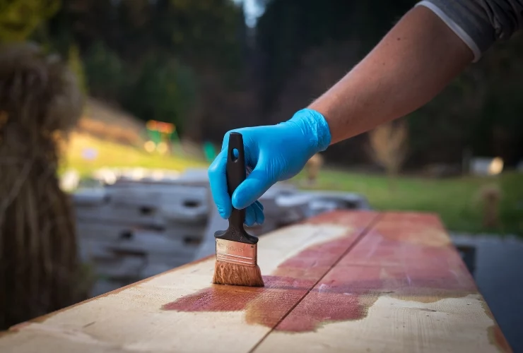 Im Garten wird Holz gestrichen, um es dauerhaft vor Witterung zu schützen.